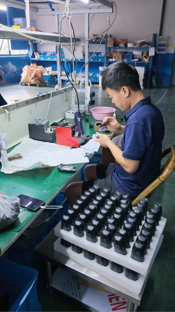 Operator assembling black shaving units at a production workstation